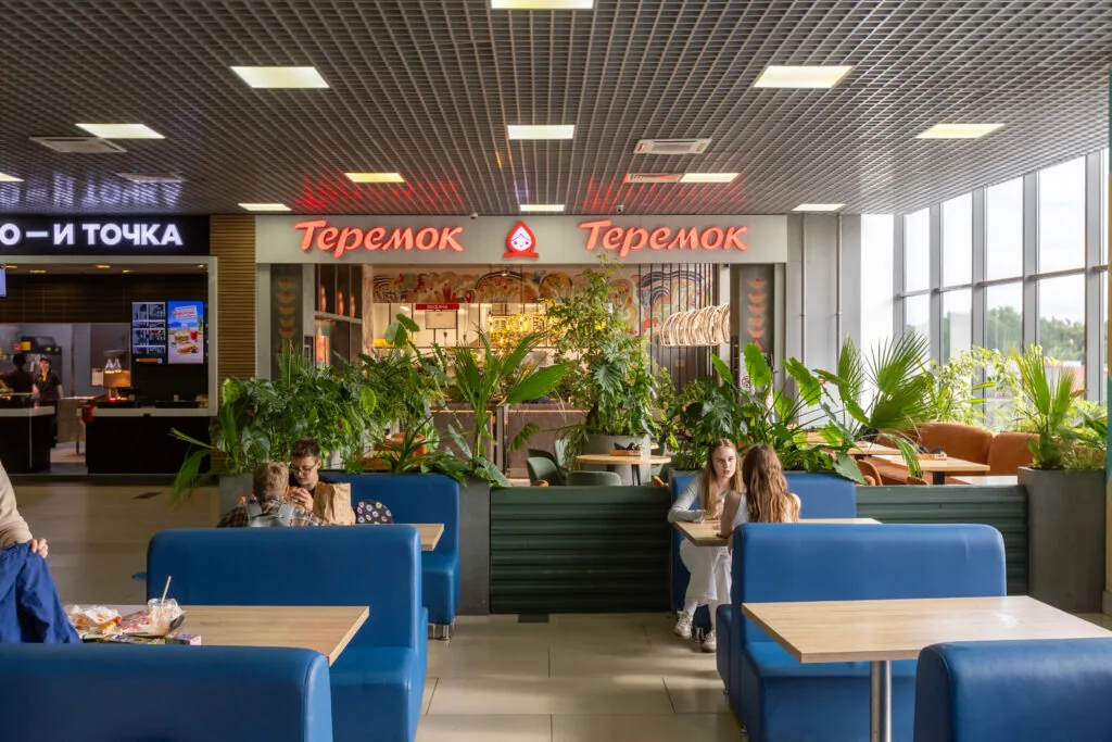 Гости за столиками на фудкорте рядом с кафе «Теремок»